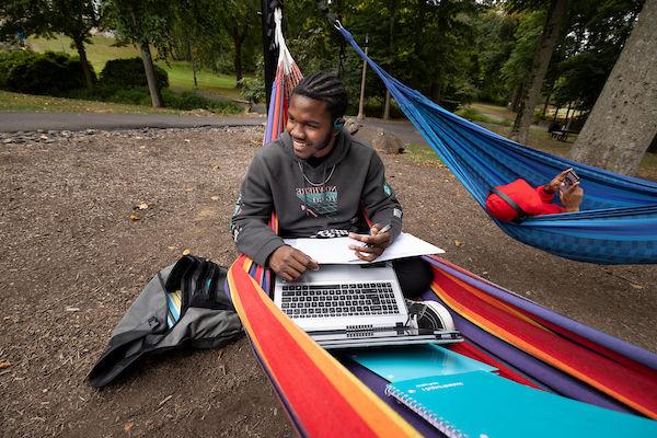 Student working on summer classes homework from Penn State Abington in a hammock